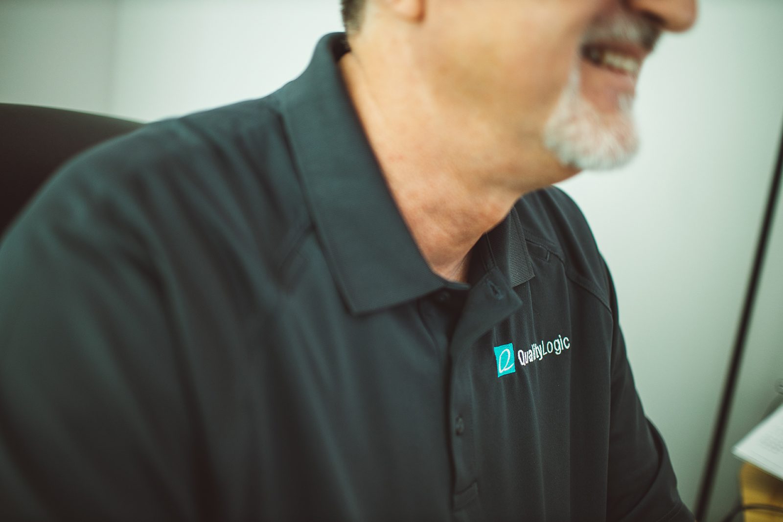 Smiling QualityLogic team member in a company polo shirt
